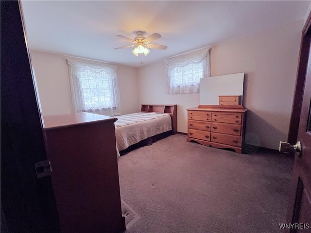 carpeted bedroom featuring ceiling fan and multiple windows