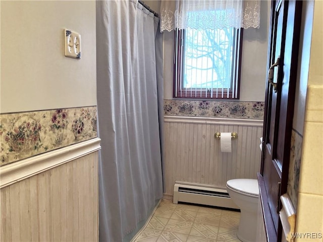 bathroom featuring a baseboard heating unit, wooden walls, and toilet