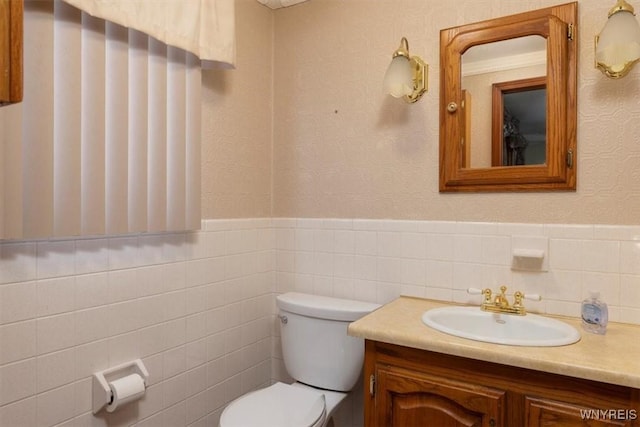 bathroom featuring vanity, toilet, and tile walls