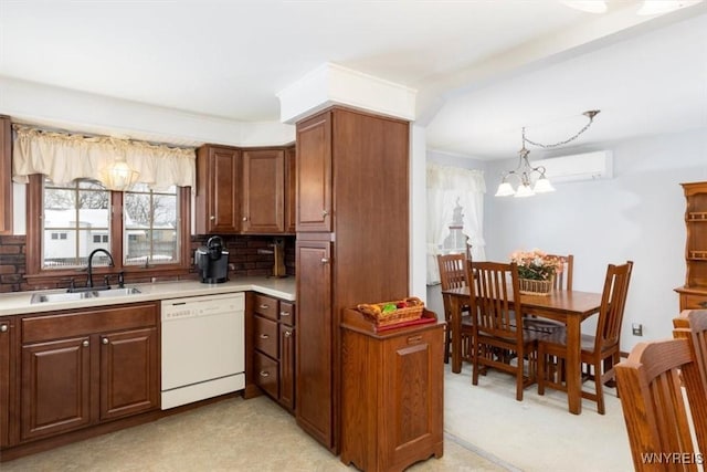 kitchen with sink, backsplash, hanging light fixtures, a wall unit AC, and white dishwasher