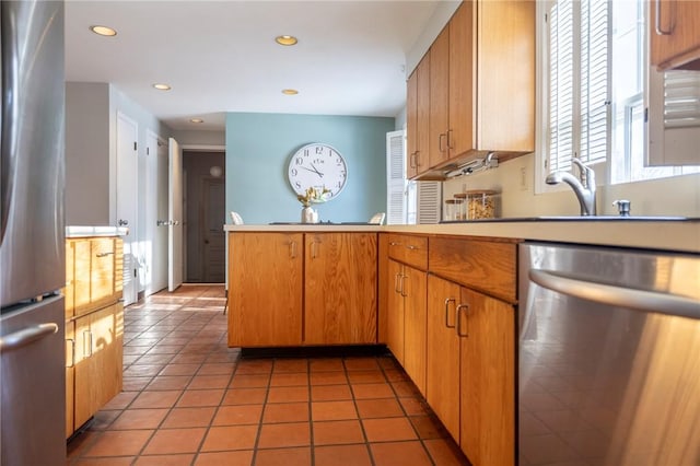 kitchen featuring light tile patterned flooring, stainless steel appliances, kitchen peninsula, and sink