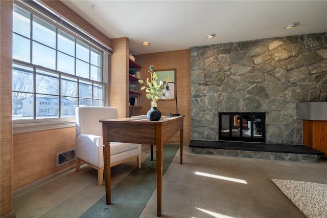 carpeted office featuring a stone fireplace