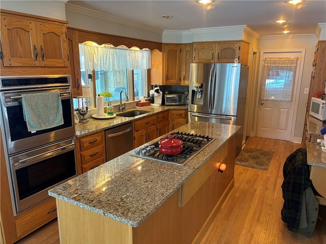 kitchen with sink, light hardwood / wood-style flooring, stainless steel appliances, light stone counters, and ornamental molding