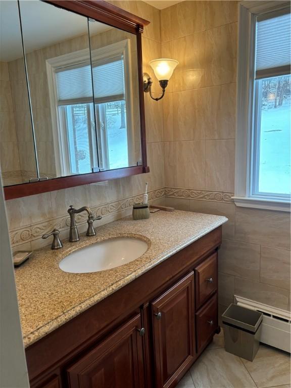 bathroom with tile walls, vanity, and a baseboard heating unit