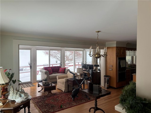 living room with sink, crown molding, wood-type flooring, and a notable chandelier