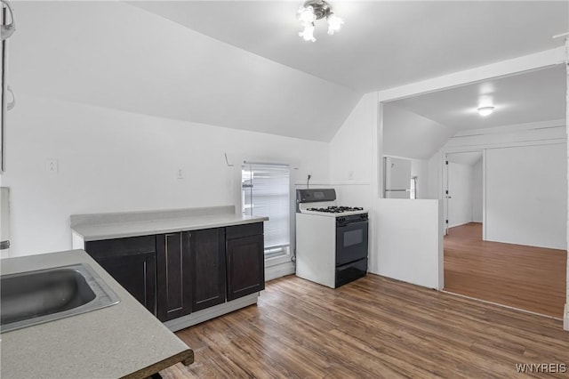 kitchen with white gas range, sink, hardwood / wood-style floors, and lofted ceiling