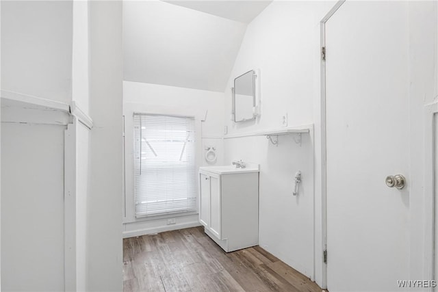 bathroom featuring wood-type flooring, vaulted ceiling, and vanity