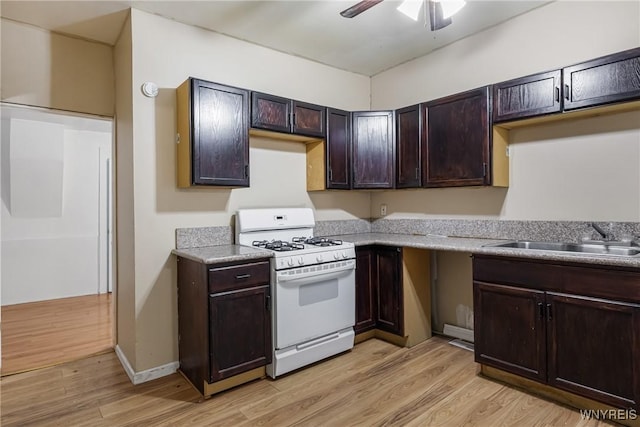 kitchen featuring sink, dark brown cabinets, gas range gas stove, and light wood-type flooring