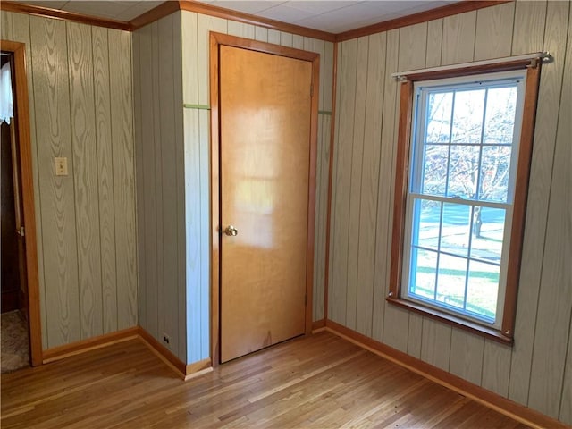 unfurnished bedroom with a closet, wood walls, and light hardwood / wood-style flooring