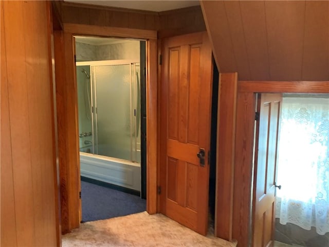 hallway featuring light carpet and wooden walls