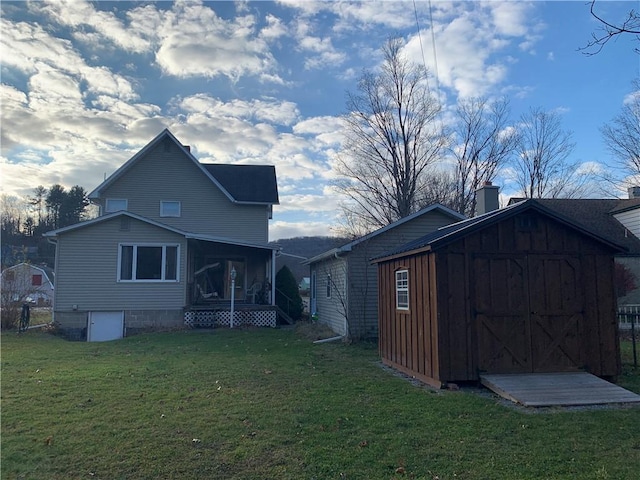 rear view of house with a yard, a sunroom, and a shed