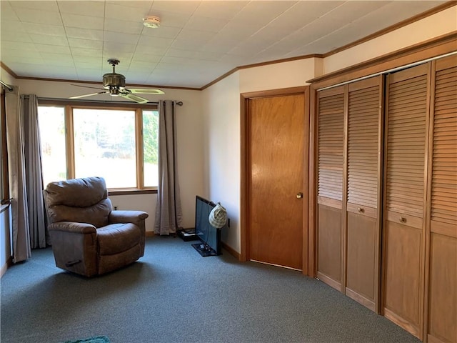 living area featuring ornamental molding, carpet flooring, and ceiling fan