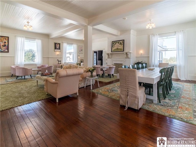 dining area featuring beam ceiling, dark wood-type flooring, a fireplace, and a chandelier