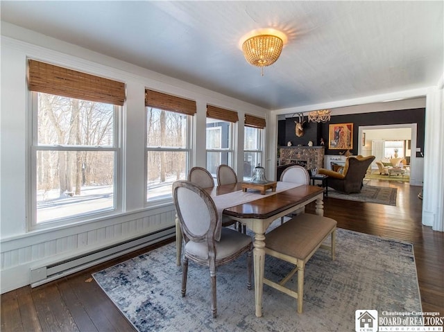 dining room with dark wood-type flooring, a baseboard radiator, and a brick fireplace