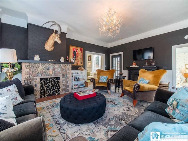 living room featuring hardwood / wood-style flooring, a fireplace, an inviting chandelier, and crown molding