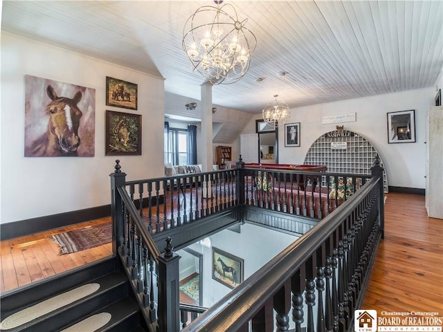 hallway with hardwood / wood-style flooring, wood ceiling, and a chandelier