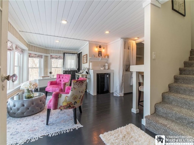 living room with crown molding, wooden ceiling, and dark hardwood / wood-style flooring