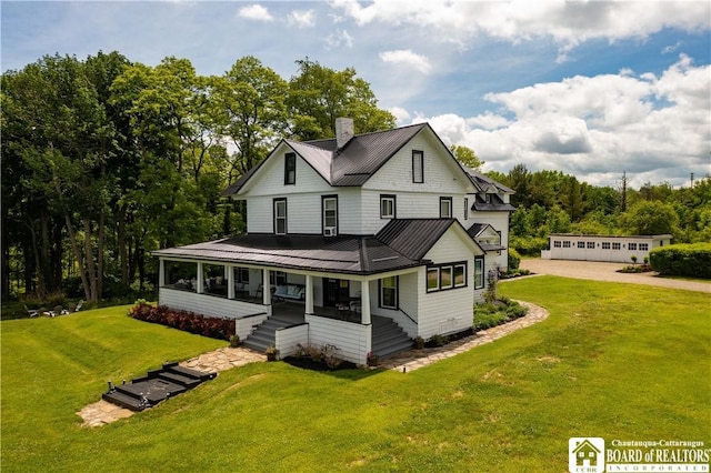 back of house featuring a garage, covered porch, and a lawn