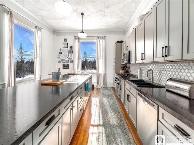 kitchen featuring sink, gray cabinetry, ornamental molding, pendant lighting, and stainless steel appliances