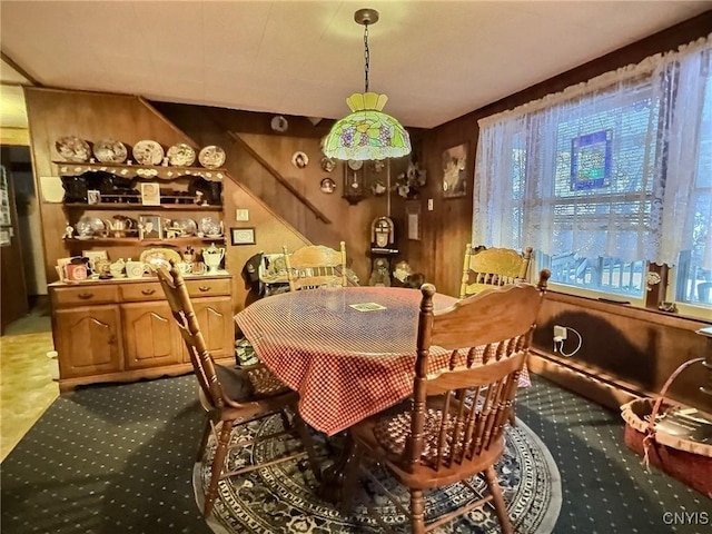 carpeted dining room with wood walls