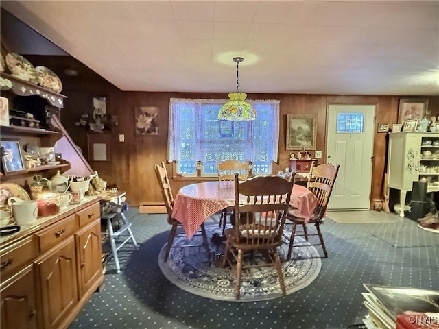 dining room with a baseboard heating unit, carpet floors, and wooden walls