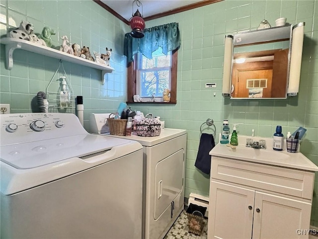 laundry area featuring ornamental molding, sink, washer and dryer, and tile walls