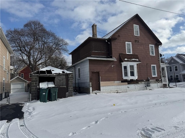 snow covered house with an outbuilding and a garage