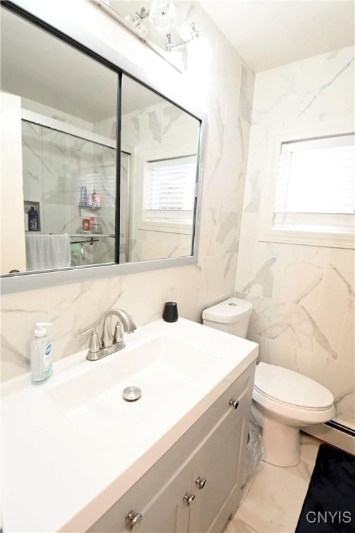 bathroom with vanity, toilet, a shower with door, and tile walls