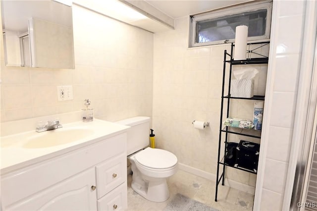 bathroom with vanity, toilet, tile patterned flooring, and tile walls