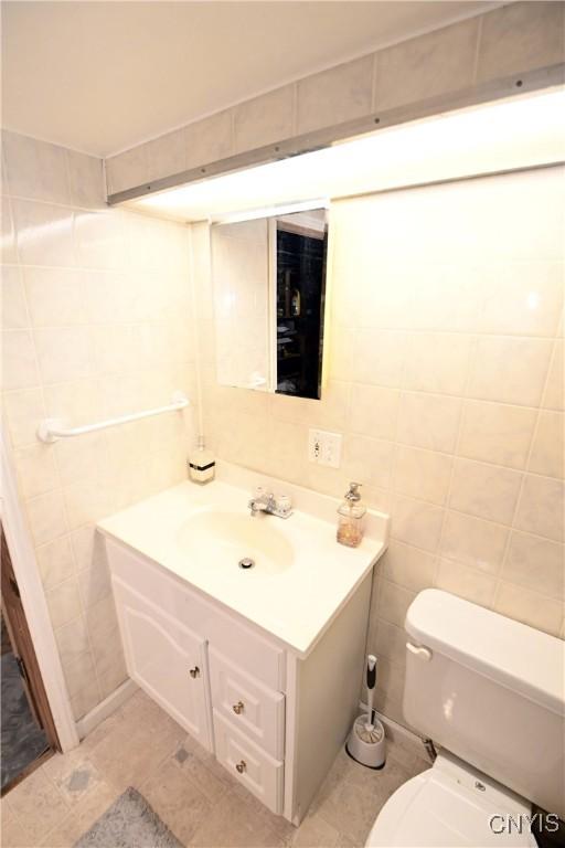 bathroom with vanity, toilet, tile patterned flooring, and tile walls