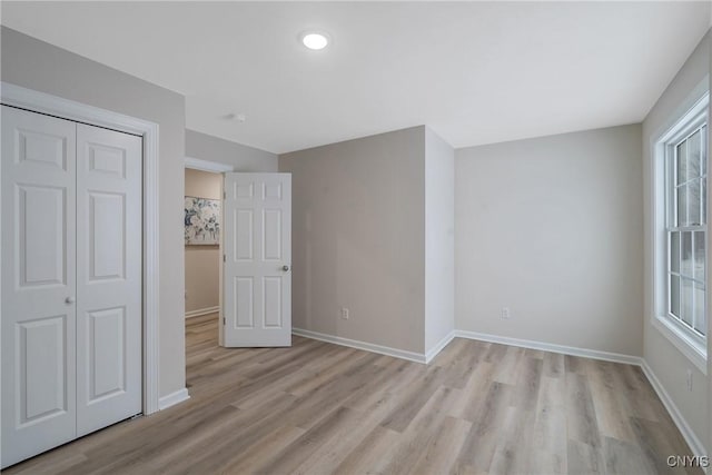 unfurnished bedroom with light hardwood / wood-style floors and a closet