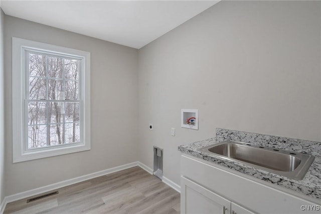 washroom with cabinets, washer hookup, a wealth of natural light, and electric dryer hookup