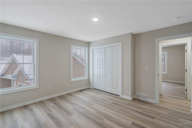 unfurnished bedroom with a closet and light wood-type flooring