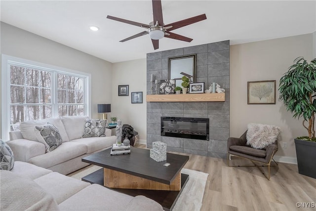 living room with hardwood / wood-style flooring, ceiling fan, and a fireplace