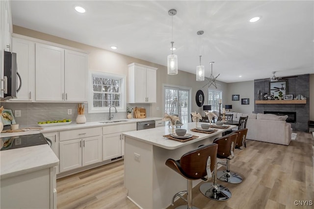 kitchen with sink, white cabinetry, decorative light fixtures, a kitchen island, and stainless steel appliances