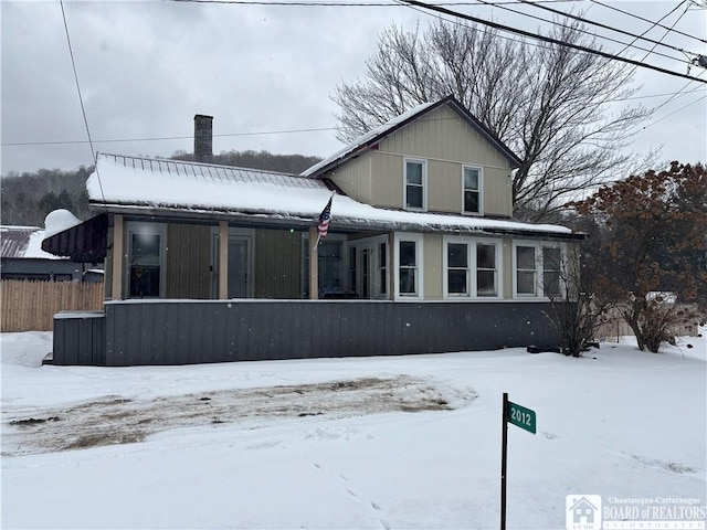 snow covered property with covered porch