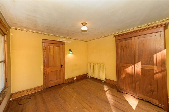 unfurnished room featuring radiator and hardwood / wood-style flooring