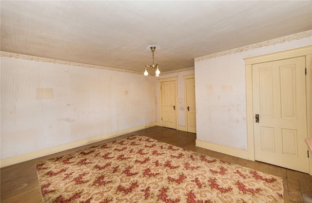 spare room featuring dark hardwood / wood-style flooring and a chandelier