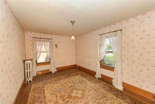 spare room featuring plenty of natural light, dark wood-type flooring, and radiator heating unit