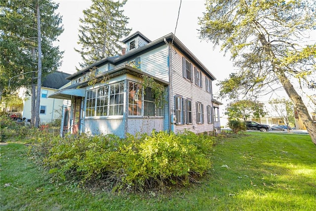 view of property exterior with a yard and a sunroom