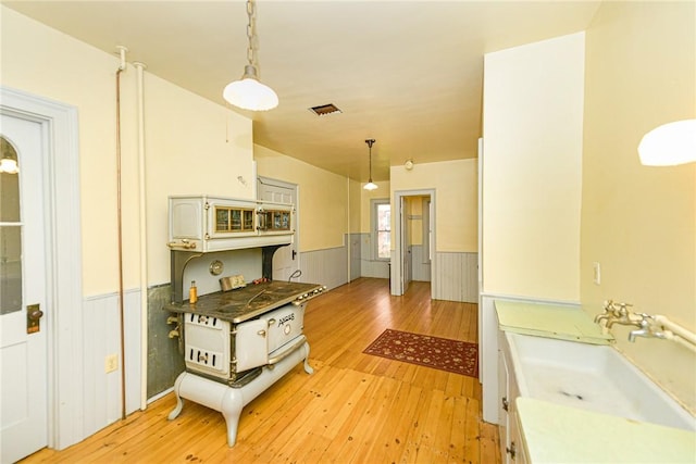 kitchen featuring white cabinetry, hanging light fixtures, and light hardwood / wood-style flooring