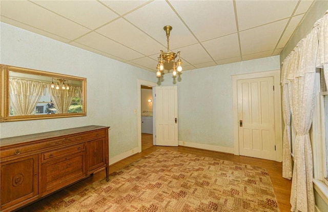 empty room with a chandelier, a paneled ceiling, and light wood-type flooring