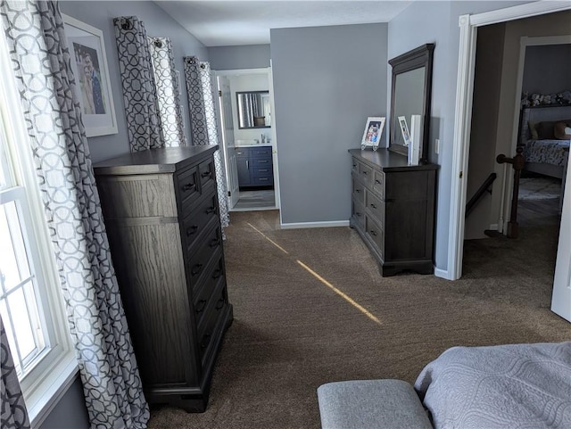 bedroom with ensuite bathroom, sink, and dark carpet