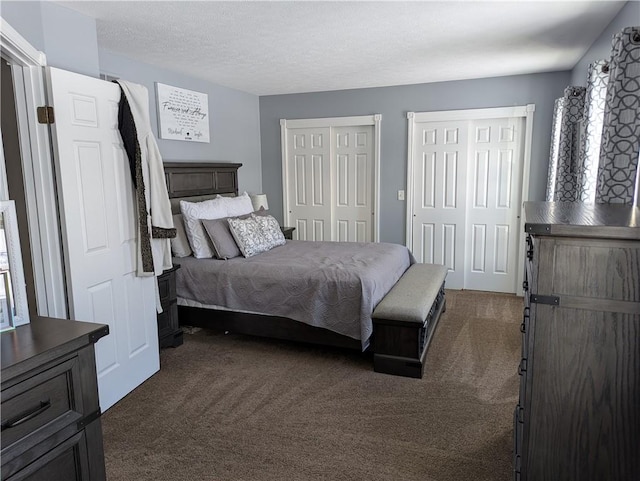 bedroom with dark carpet, two closets, and a textured ceiling