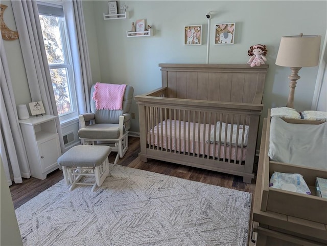 bedroom with dark hardwood / wood-style flooring and a crib