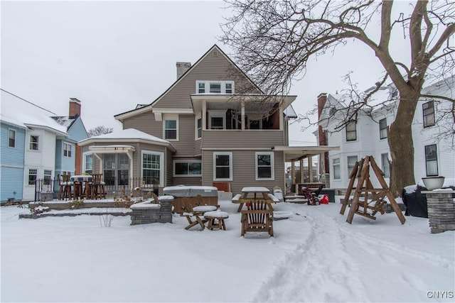 snow covered back of property featuring a hot tub