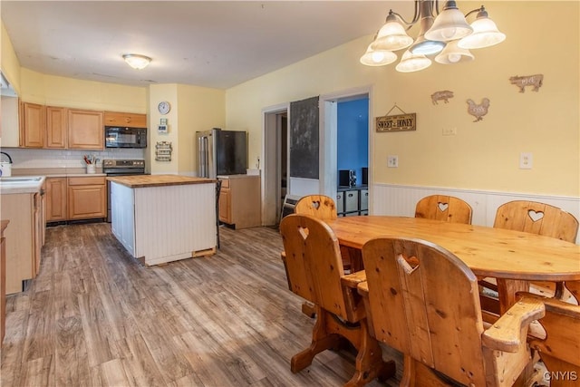 kitchen with a kitchen island, appliances with stainless steel finishes, sink, hanging light fixtures, and light brown cabinets