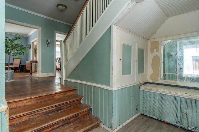 stairs with hardwood / wood-style flooring, ornamental molding, radiator heating unit, and vaulted ceiling