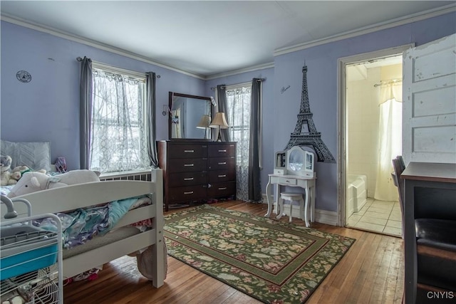 bedroom featuring ornamental molding, ensuite bathroom, hardwood / wood-style floors, and multiple windows