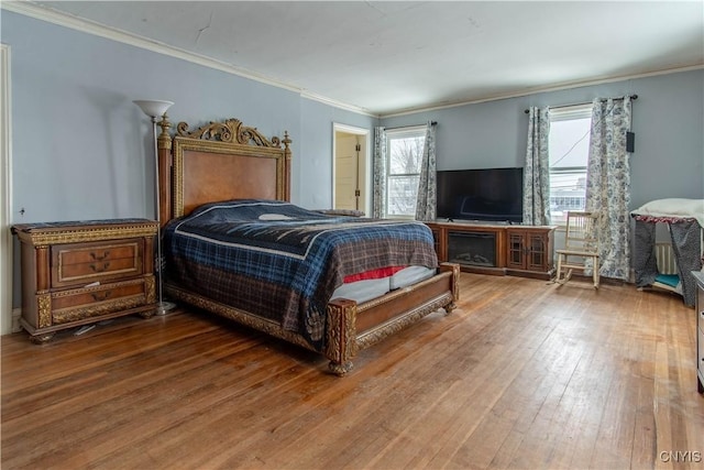 bedroom featuring multiple windows, wood-type flooring, and ornamental molding